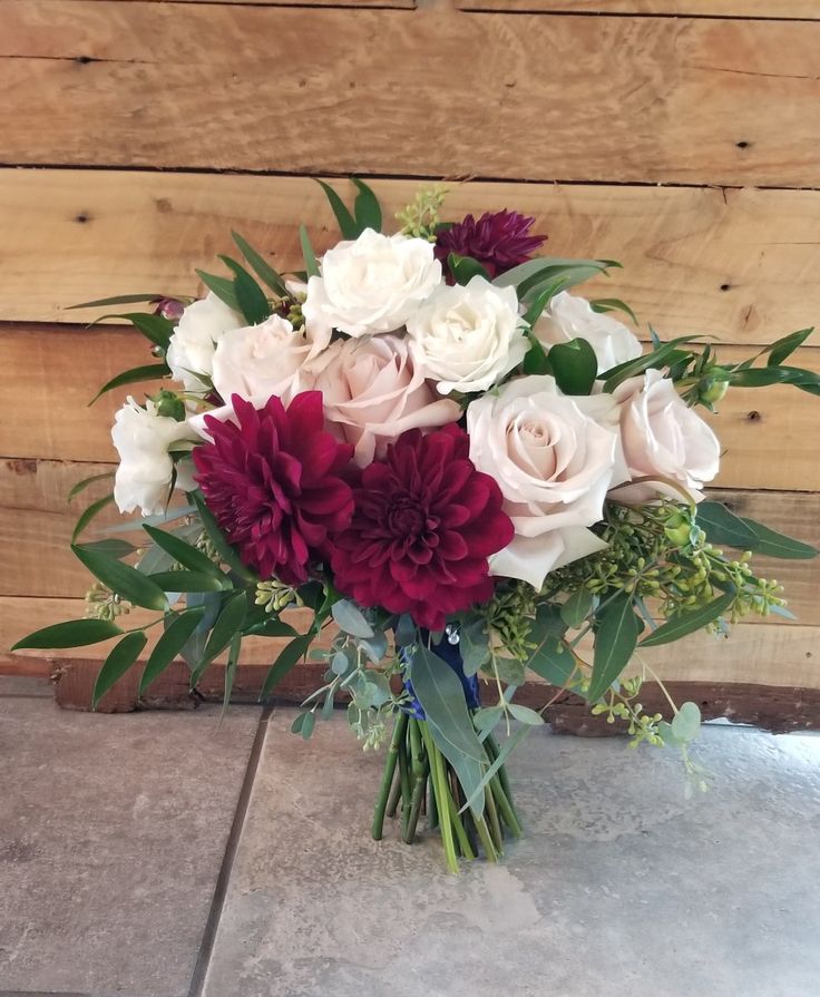 a bouquet of flowers sitting on top of a tile floor next to a wooden wall