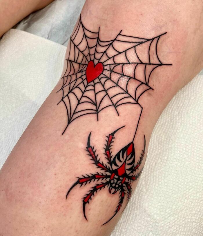 a spider web tattoo on the leg with a heart in it's center and two legs