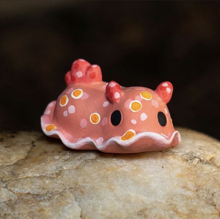 a pink and orange toy sitting on top of a rock