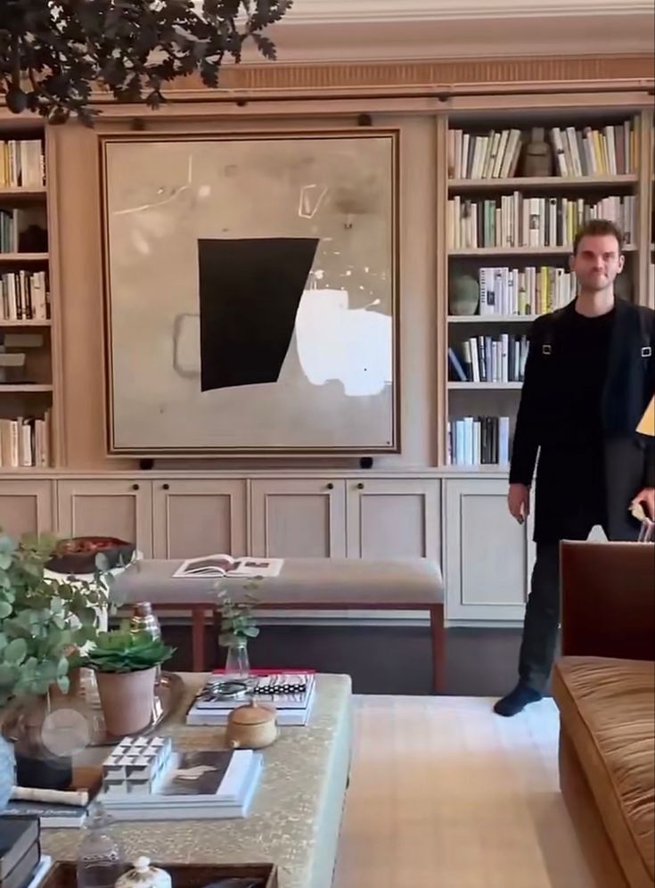 a man standing in front of a living room filled with furniture and bookshelves