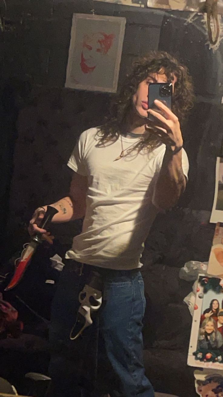 a young man taking a selfie in front of a mirror with his cell phone