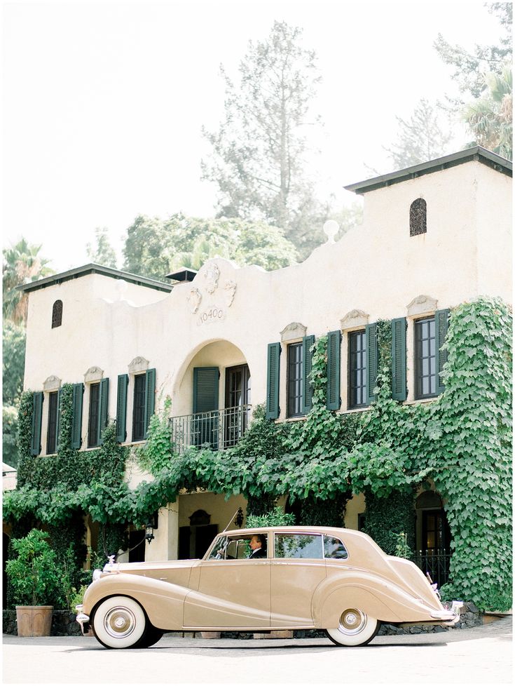 an old car is parked in front of a building with ivy growing on the walls