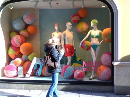 a woman walking past a store window with mannequins in it