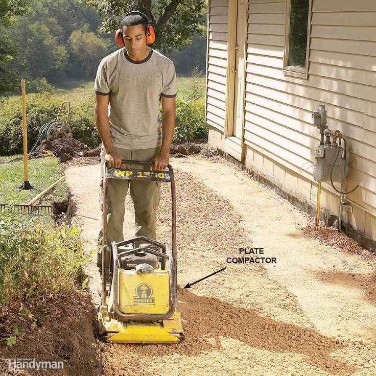 a man standing in front of a house with a lawn mower attached to it