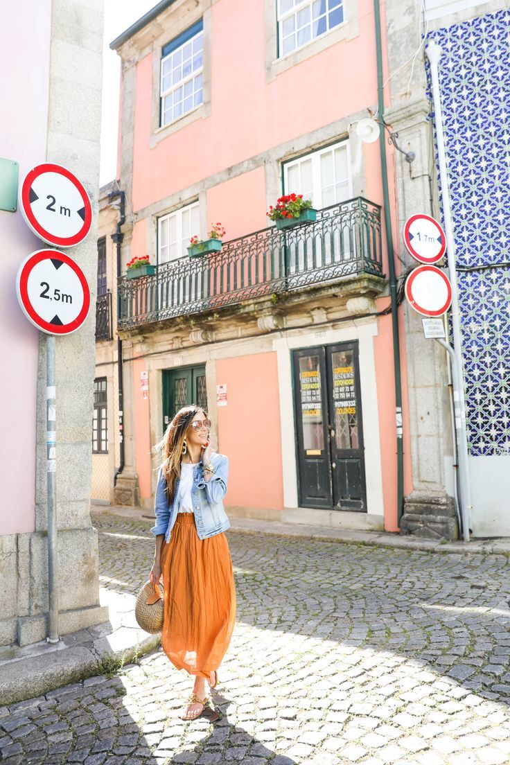 a woman in an orange dress is walking down the street