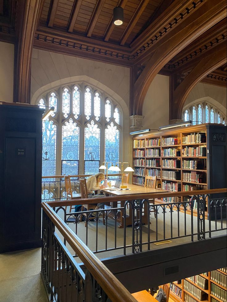 an old library with many bookshelves and tables in the center, along with large windows