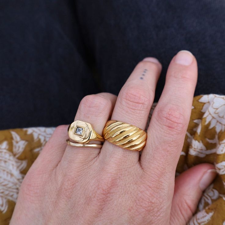 Whether worn as a standalone statement piece or stacked with other rings for a bolder look, the Striated Gold Ring effortlessly complements any ensemble, from casual to formal. 18kt gold plated stainless steel Color variations may exist compared to the jewelry photographed. Everyday Yellow Gold Metal Ring, Everyday Yellow Gold Rings, Gold Wide Band Ring Tarnish Resistant For Everyday, Everyday Metal Rings With Polished Finish, Everyday Gold Wide Band Ring, Tarnish Resistant, Elegant Gold Signet Ring, Classic Everyday Metal Rings, Gold Wide Band Jewelry For Everyday, Gold Open Ring For Everyday