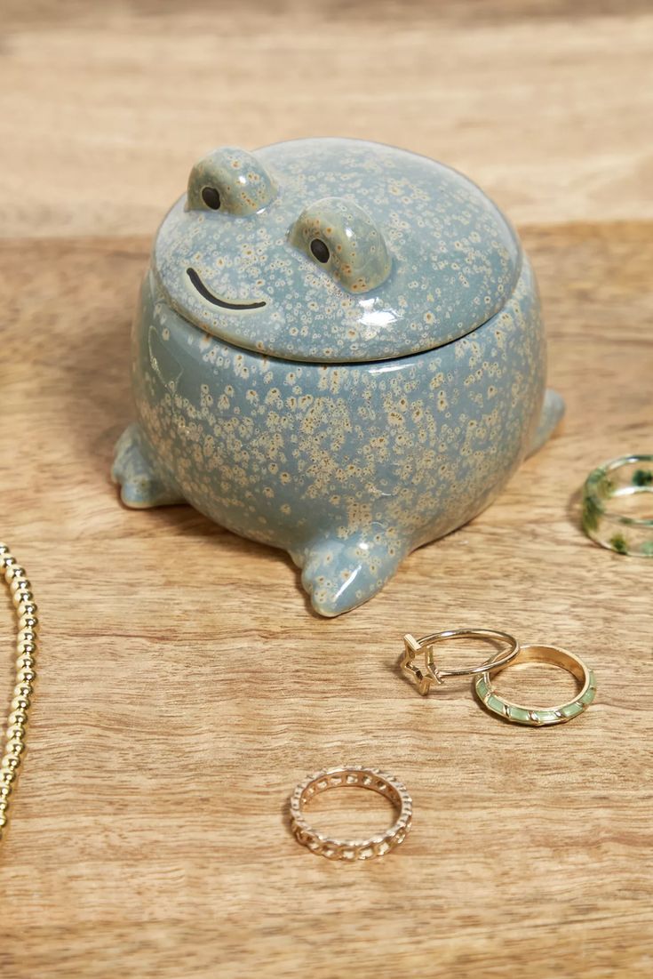 a blue ceramic pig with gold rings and other jewelry on a wooden table next to it