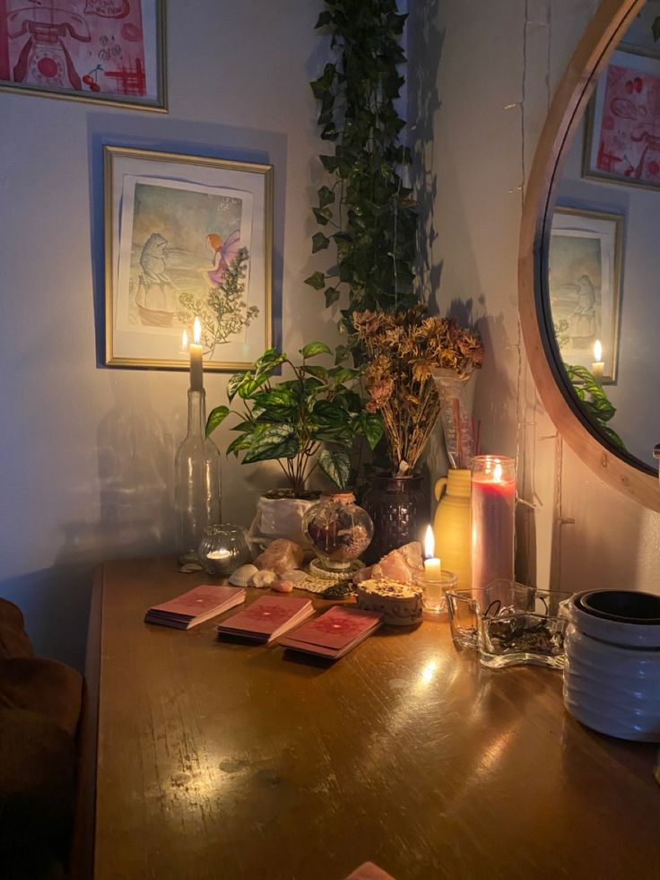 a wooden table with candles and pictures on the wall next to it in front of a mirror