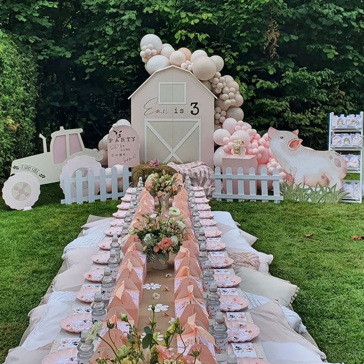 an outdoor table set up for a baby shower party with pink and white decorations on it