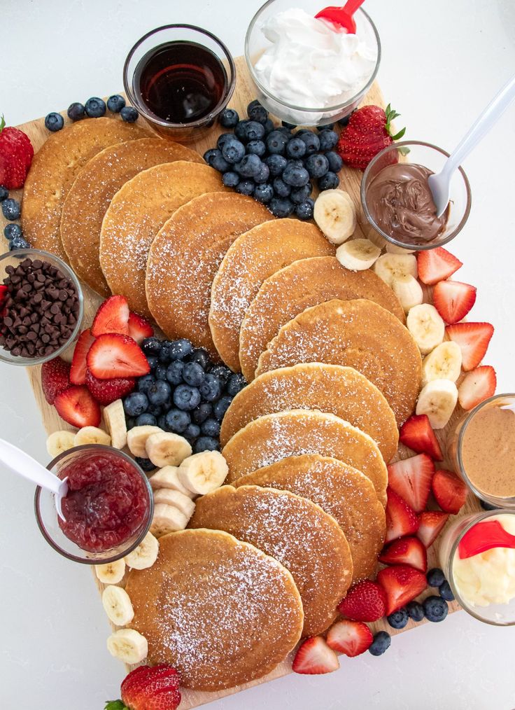 a platter with pancakes, fruit and dips on it is shown in this image