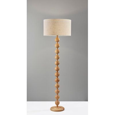 a wooden floor lamp with a white shade on it's base and a beige linen lampshade