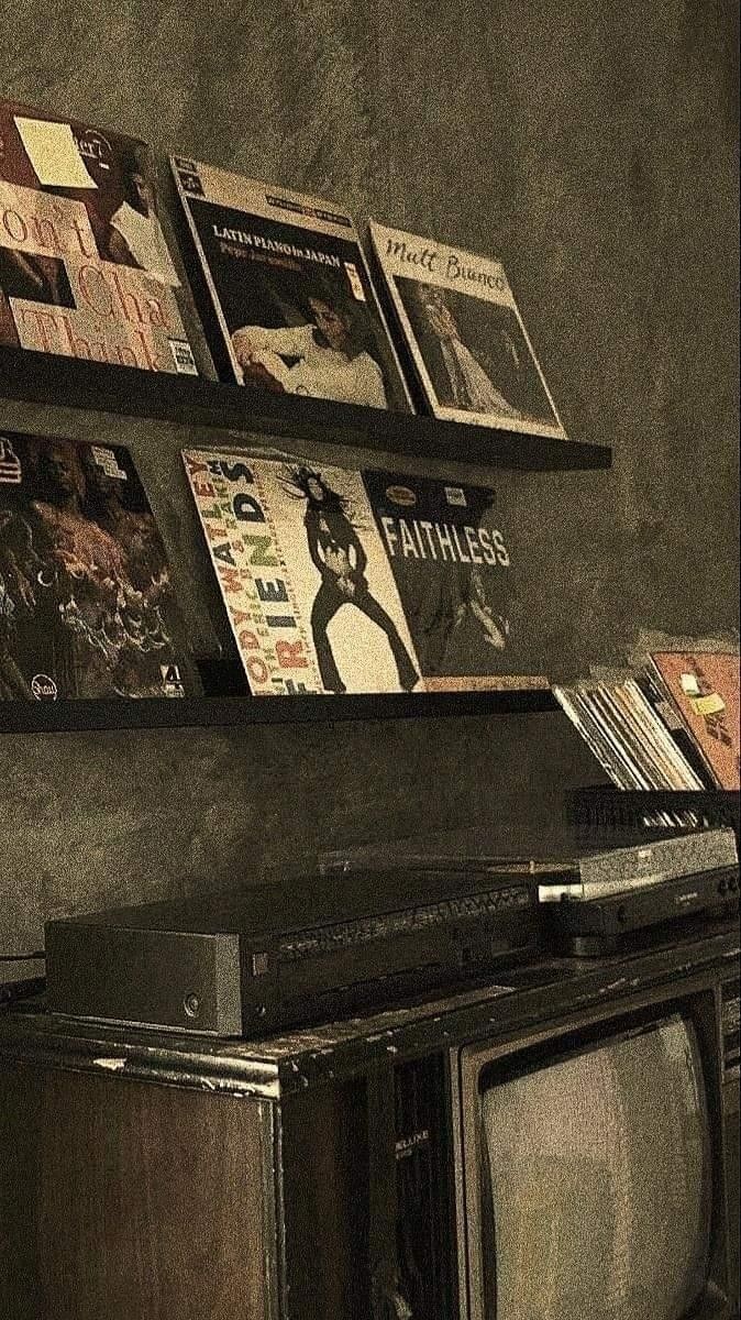 an old tv sitting on top of a wooden cabinet next to a shelf filled with cd's