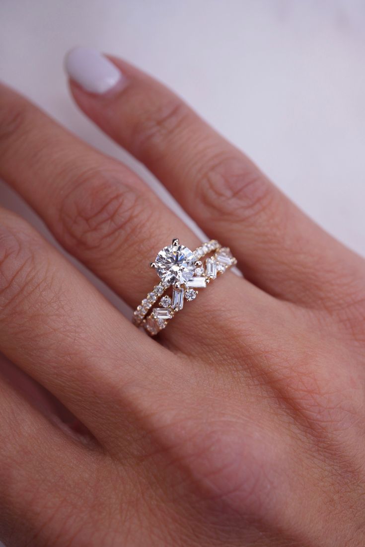 a woman's hand with a diamond ring on her finger and the other hand holding an engagement ring