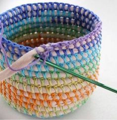 three crocheted baskets with a knitting needle in the middle one is multicolored