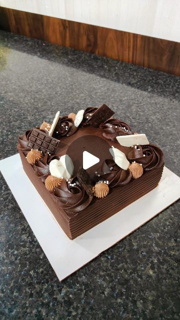 a large chocolate cake sitting on top of a white plate covered in icing and seashells