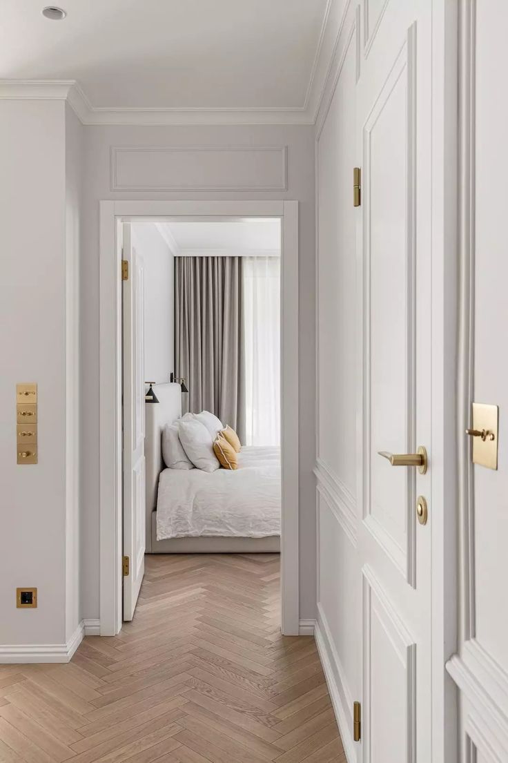 an open door leading to a bedroom with white walls and wood flooring on the other side