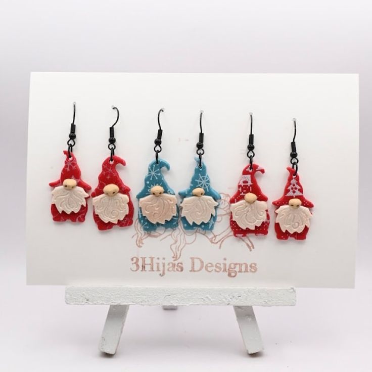 five red, white and blue gnomes are hanging from hooks on a card holder