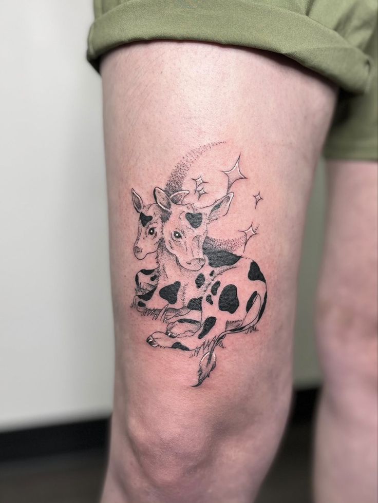 a woman's leg with a tattoo of a cow and stars on the calf