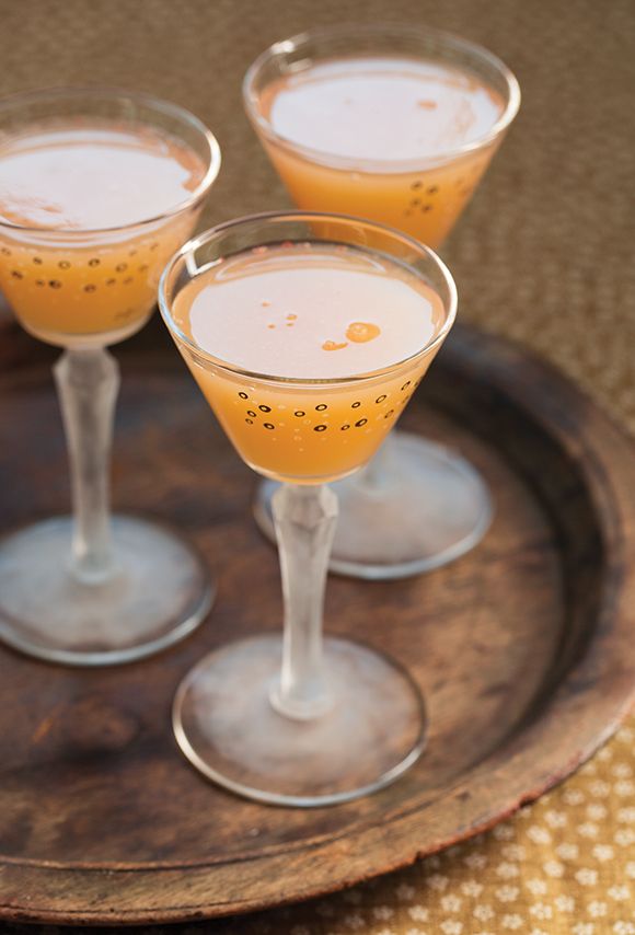 three glasses filled with drinks sitting on top of a wooden tray