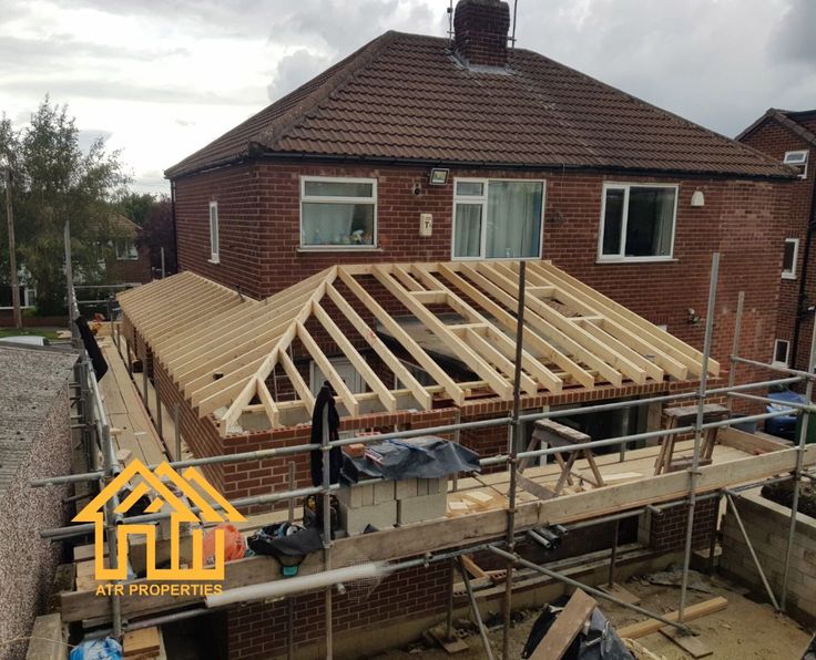 a house being built with wooden framing on the front and side of it, surrounded by scaffolding