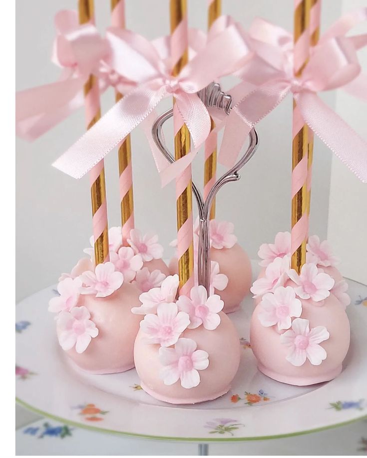 pink cake pops decorated with flowers and gold sticks