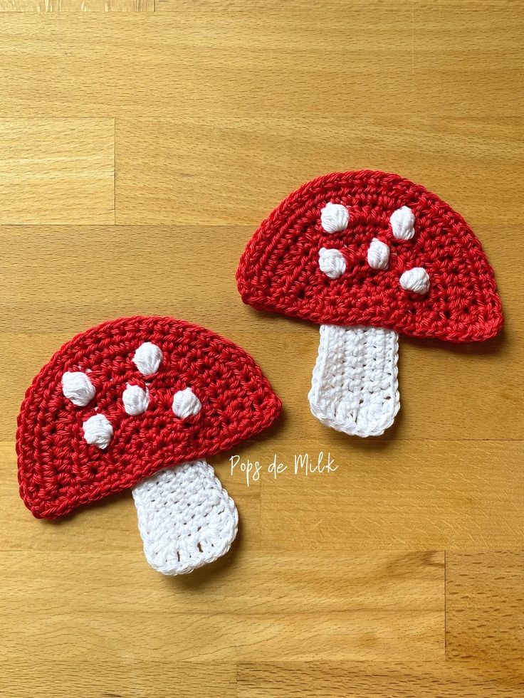 two crocheted mushrooms sitting on top of a wooden floor