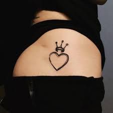 a heart with a crown tattoo on the back of her left shoulder and right arm