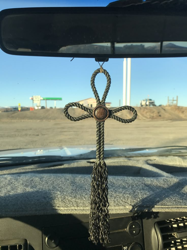 a car dashboard with a steering wheel and a cross hanging from it's center console