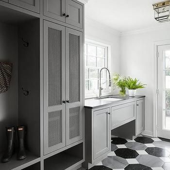 a kitchen with black and white tile flooring and cabinetry, along with potted plants