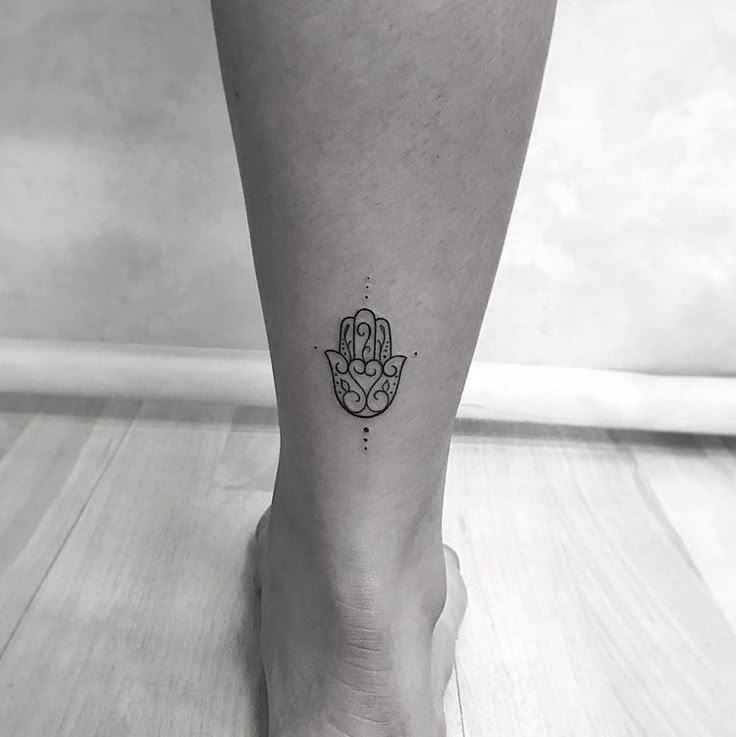 a black and white photo of a foot with a hamsa tattoo on it