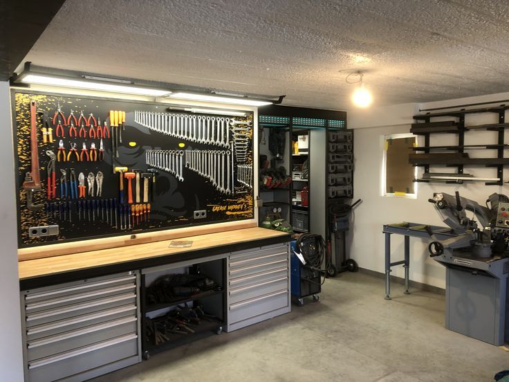 a garage with many tools and equipment on the wall, including workbench cabinets