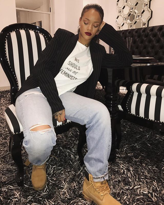 a woman sitting in a chair with ripped jeans