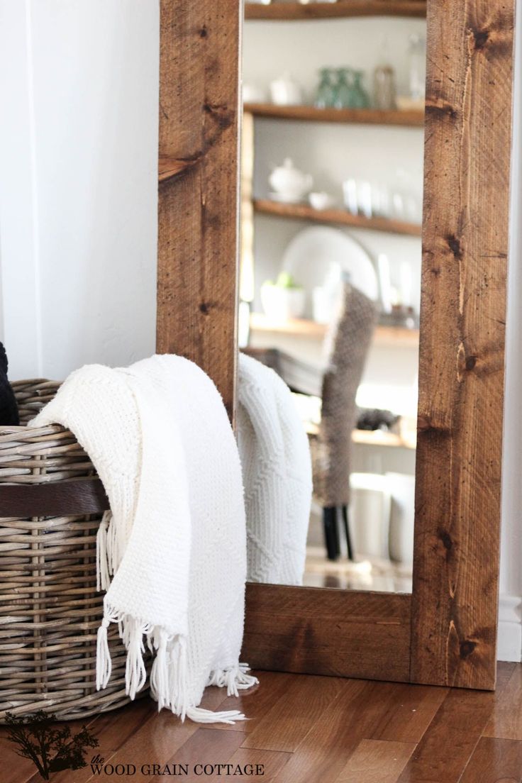 a mirror sitting on top of a wooden floor next to a basket filled with towels