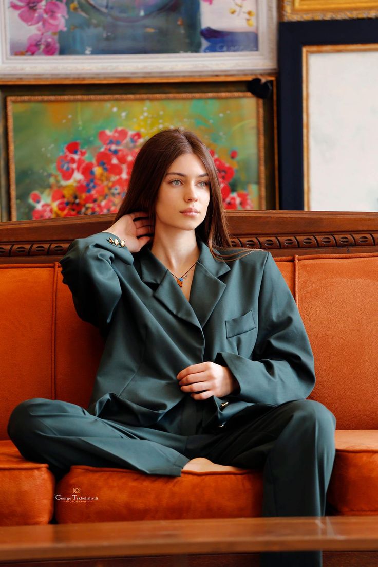 a woman sitting on top of a brown couch next to pictures hanging on the wall