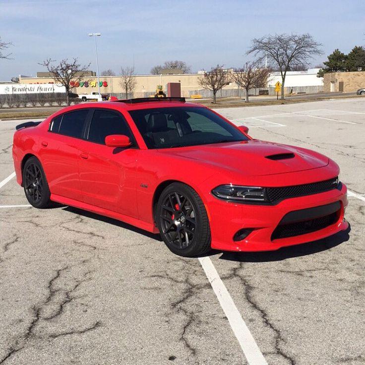 a red dodge charger parked in a parking lot with no one around the car