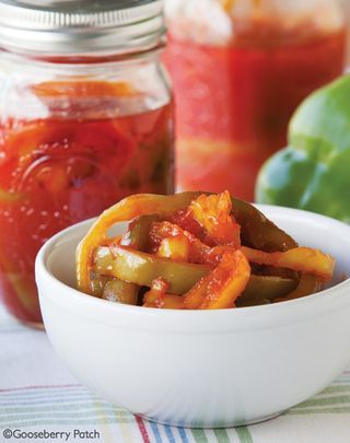 a bowl filled with peppers next to jars of pickles