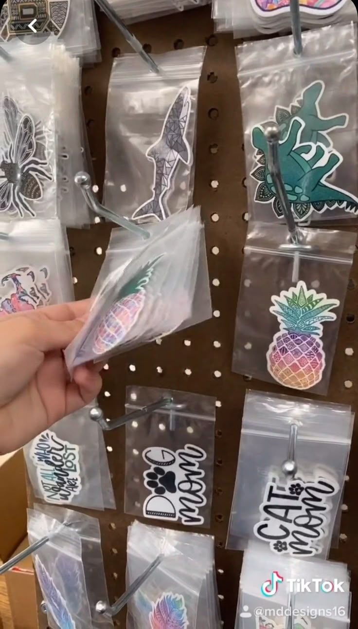 someone is holding up some stickers in their hand and they are on the shelf