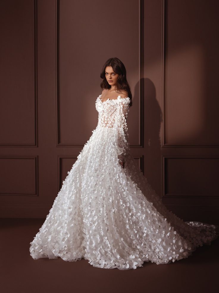 a woman in a white wedding dress standing against a wall