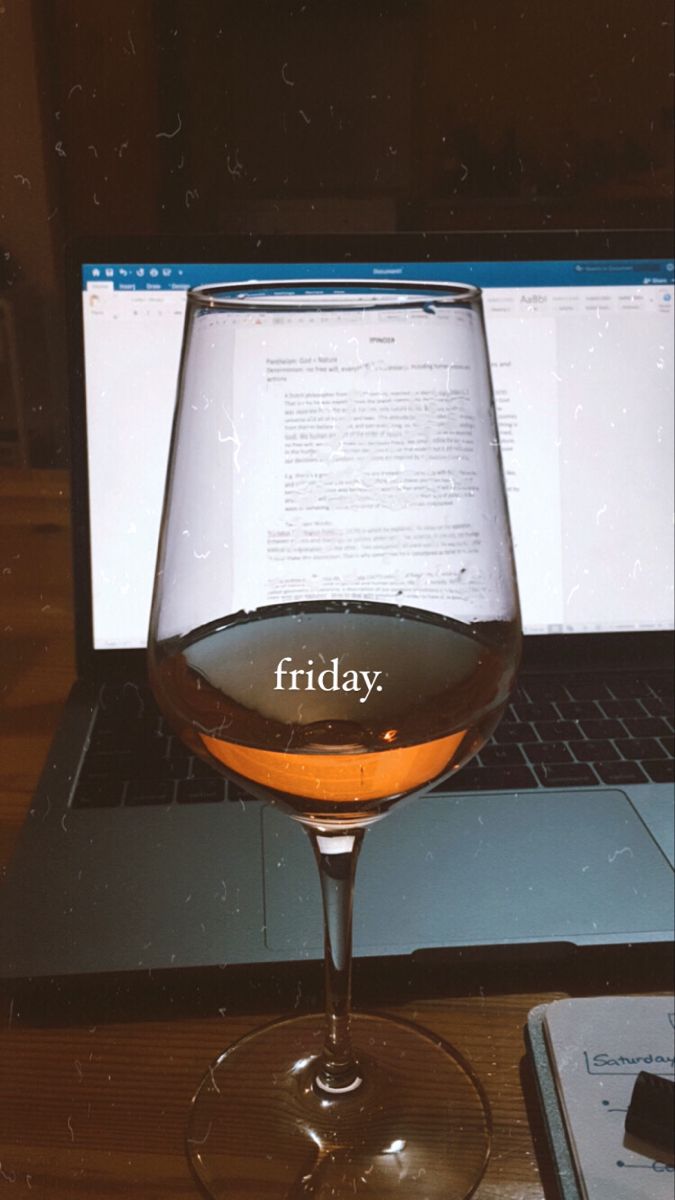 a glass of wine sitting in front of a laptop with the word friday written on it