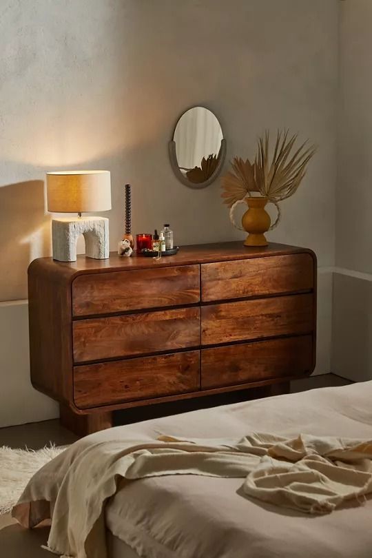 a bedroom with a bed, mirror and lamp on the side table in front of it