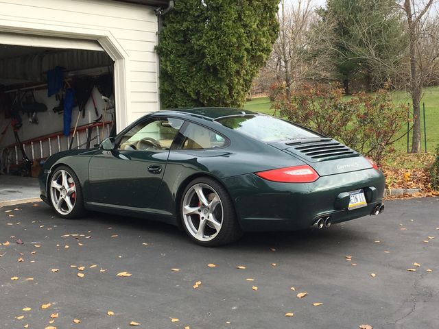 a green sports car parked in front of a garage