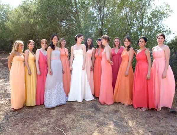 a group of women standing next to each other in long dresses on a dirt ground