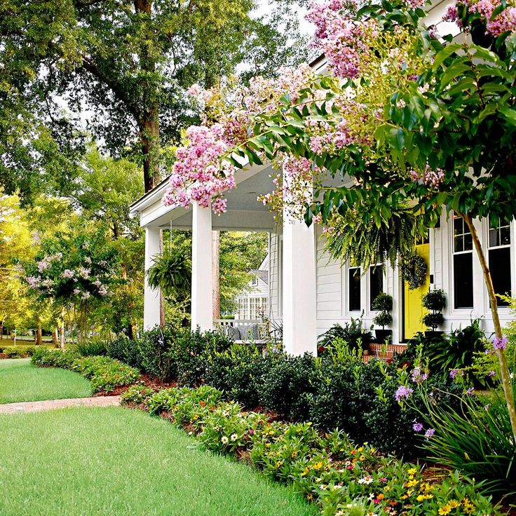 a white house surrounded by trees and flowers