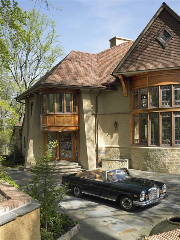 a black car is parked in front of a large house with wood trimmings