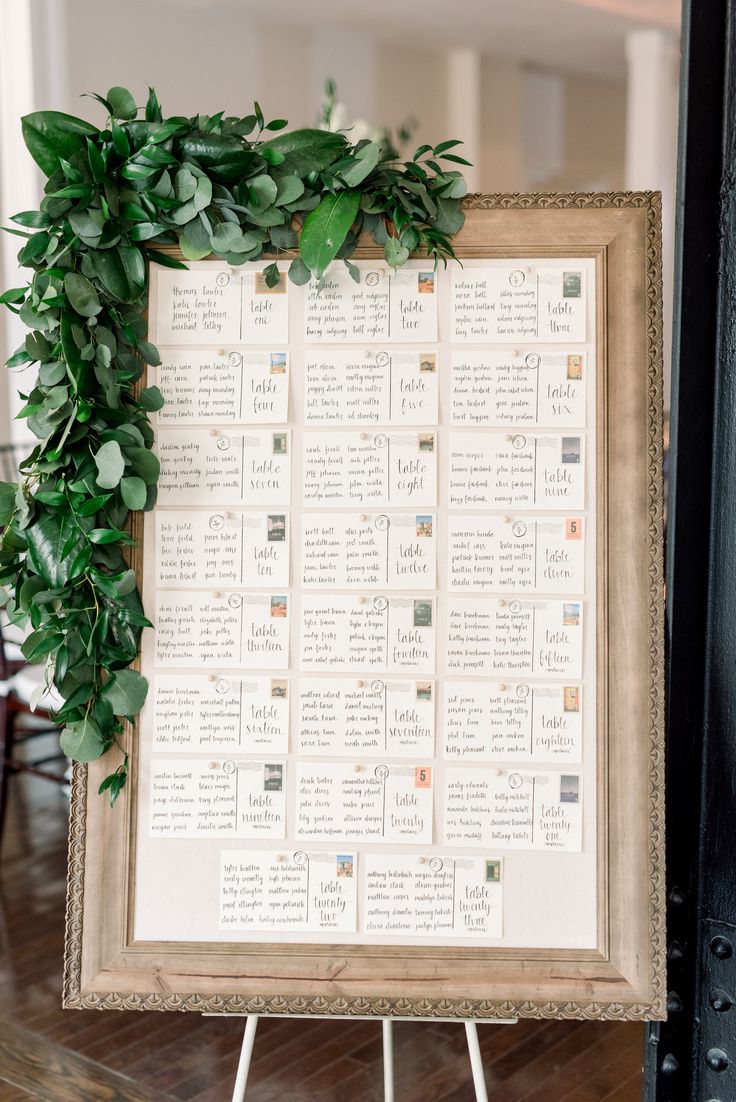 a wedding seating chart with greenery on it