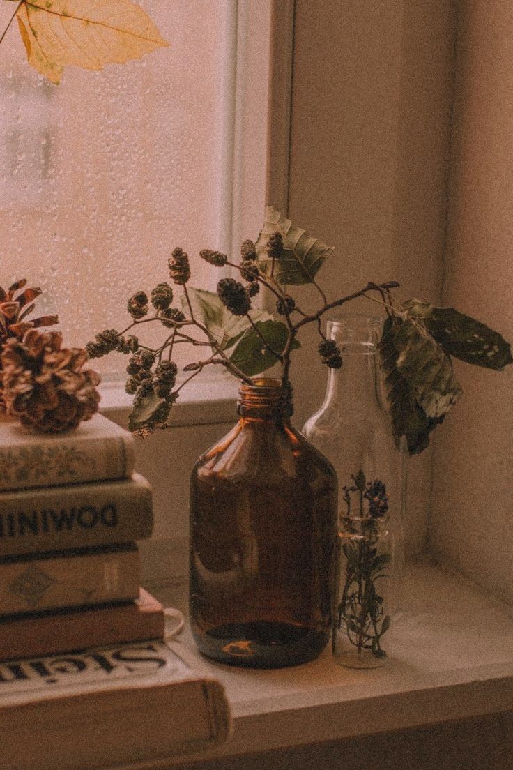 some books are sitting on a window sill next to a vase with flowers in it