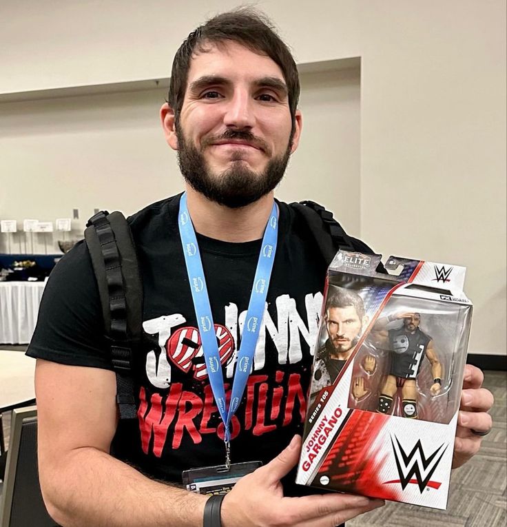 a man holding a wrestling figure in his hand and a box with the wrestler on it