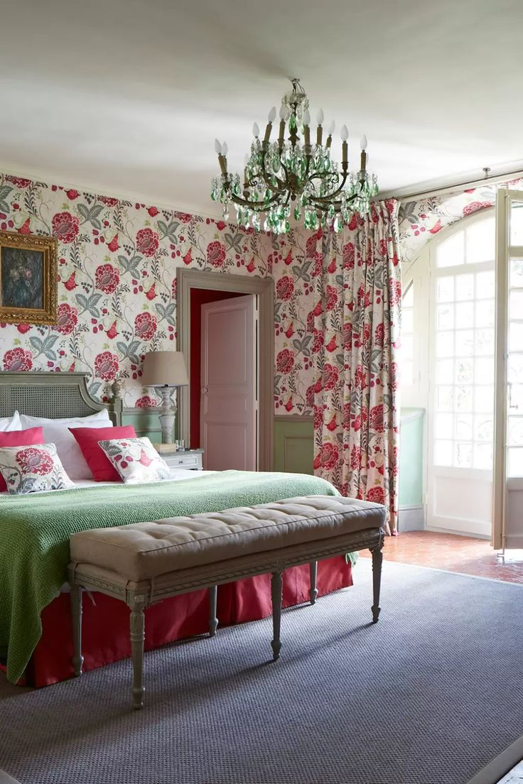 a bedroom with floral wallpaper and a chandelier