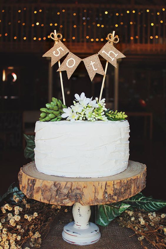 a white cake topped with succulents and two wooden signs